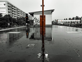 Wet road in city against sky