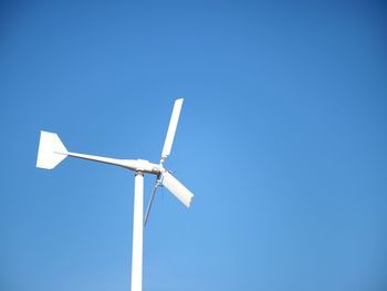 Low angle view of windmill against clear blue sky