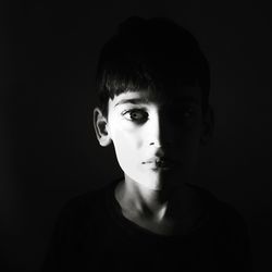 Portrait of boy against black background
