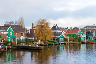 Buildings by river against sky