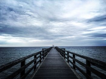 Pier over sea against cloudy sky