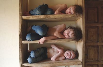 Shirtless boys in wooden shelves at home