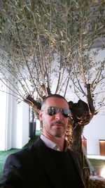 Portrait of man wearing sunglasses against trees