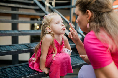 Side view of young woman sitting on railing