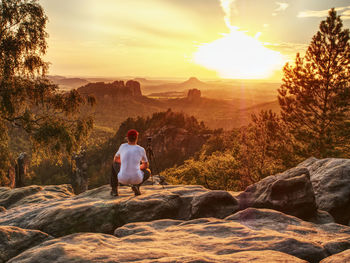 Nature photographer takes photos on peak of saxon rock. mirror camera and tripod.  sunset at dresden