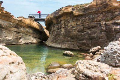 Rock formation by river against sky