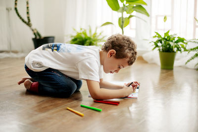 A little boy draws, lying on the floor, having fun. happy childhood, positive emotions. side view