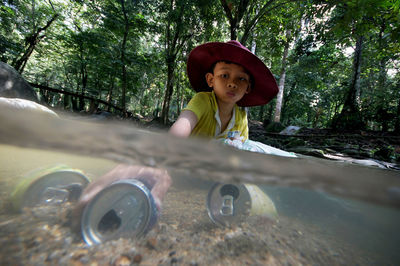 Cute boy playing with cans in river