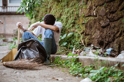 Rear view of young woman sitting on rock