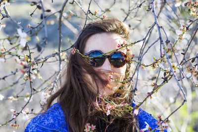 Almond tree flowers and branch and young ginger women portrait, spring tree view