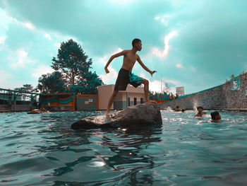 Man jumping in swimming pool against sky