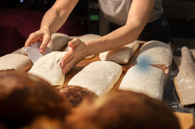 Close-up of female hands kneading dough for making artisan bread at home bakery