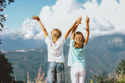 Rear view of women standing on mountain against sky