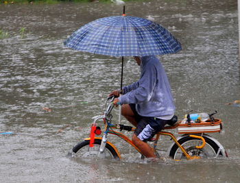 Rear view of man holding umbrella