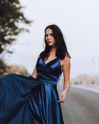 Young woman in blue dress standing on road