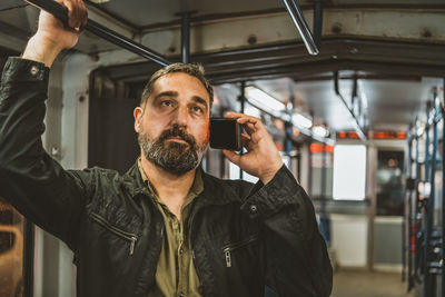 People, lifestyle, travel and public transport. attractive man talking on the phone in public bus.