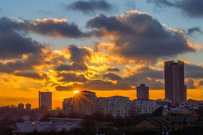 Modern buildings in city against sky during sunset