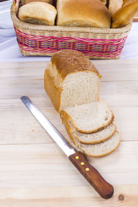 High angle view of fresh sliced breads with knife on table