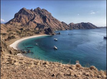 Scenic view of sea and mountains against clear blue sky