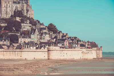 Buildings by sea against clear sky