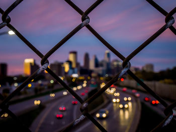 Close-up of chainlink fence against sky in city