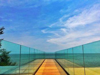 Empty footpath by railing against sky