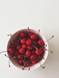 Directly above shot of cherries in bowl against white background