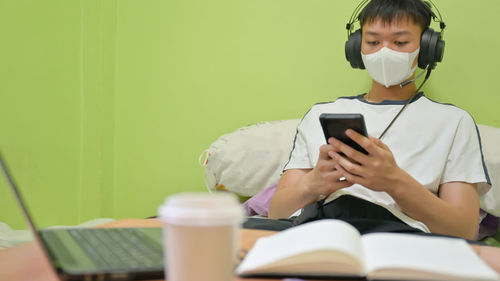 Young man using mobile phone while sitting on table
