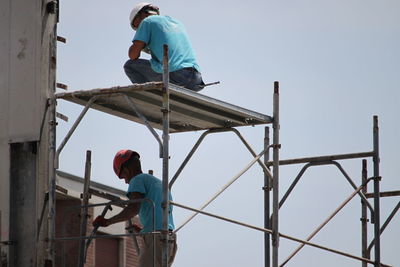 Low angle view of man working against clear sky