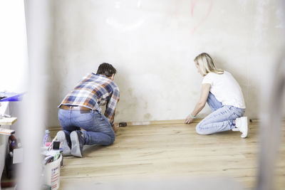 Full length of couple doing carpentry work at home