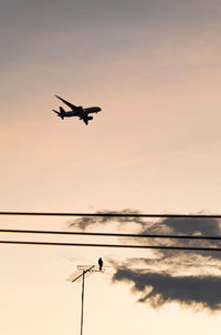 Low angle view of silhouette airplane against sky during sunset