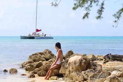 Rear view of woman sitting on beach