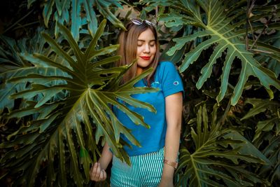 Beautiful young woman standing against plants