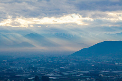 Aerial view of townscape and mountains against sky