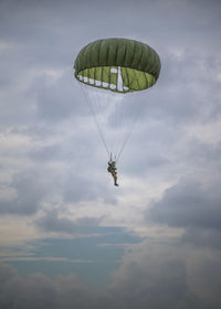 Low angle view of paratrooper against cloudy sky