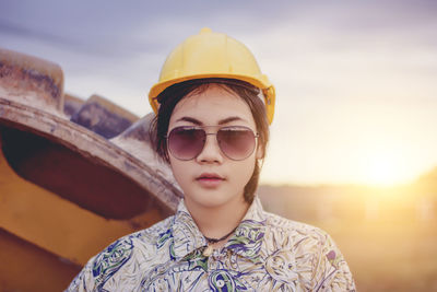 Portrait of woman wearing sunglasses standing against sky during sunset