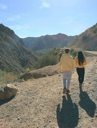 Rear view of people walking on mountain road