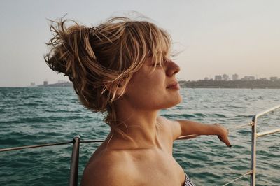 Close-up of young woman on boat in sea during sunset