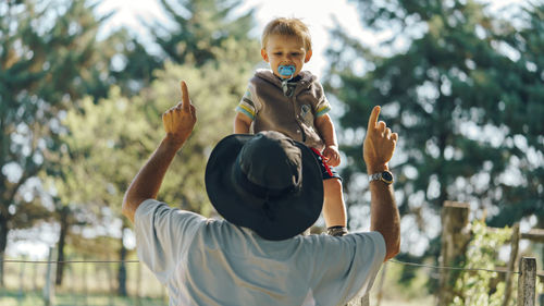 Cute baby boy looking at father dancing in forest