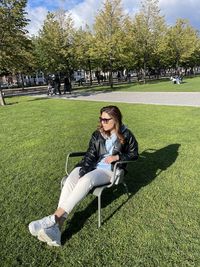 Young woman using phone while sitting on grass in park