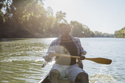 Man rowing on lake against sky