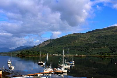 Sailboats moored on lake against sky