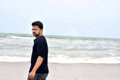 Man standing at beach against sky