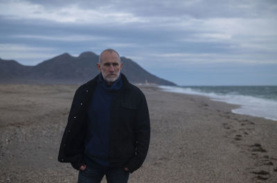 Adult man in winter clothes on beach during sunset. almeria, spain