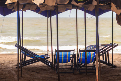 Empty chairs on beach against sky