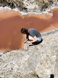 High angle view of woman crouching on rock