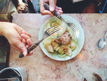 Cropped image of people having cucumber at table