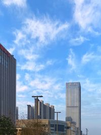 Low angle view of skyscrapers against cloudy sky