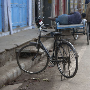Bicycle on footpath by street against buildings
