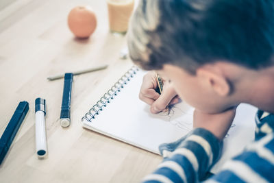 Close up view of student drawing with pencil. boy doing homework writing on a paper. kid hold pencil